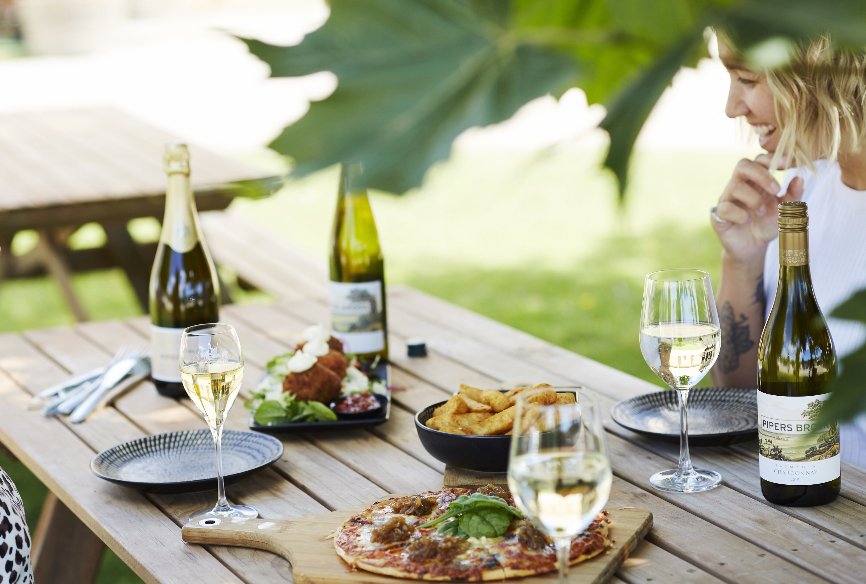 Woman seated in an table outside with food and wine